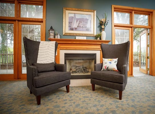 Two comfortable wingback chairs in a cozy lounge area with a fireplace.