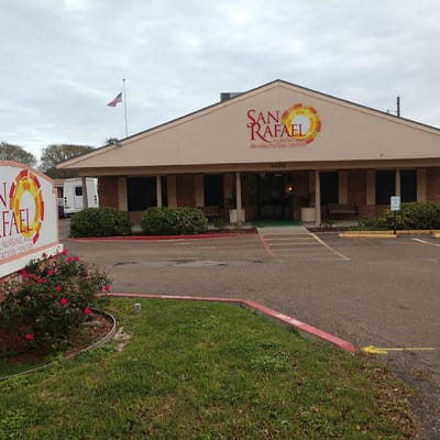 Exterior view of San Rafael Nursing and Rehabilitation Center with a sign and landscaped area