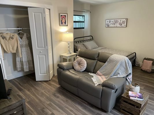 A well-furnished bedroom with a bed, seating area, and closet.