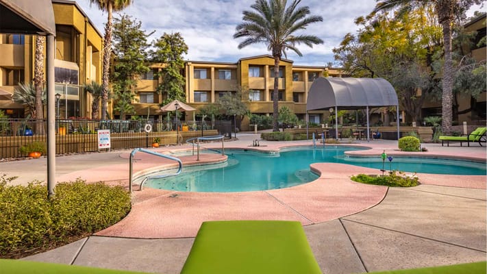 Pool area with lounge chairs surrounded by palm trees