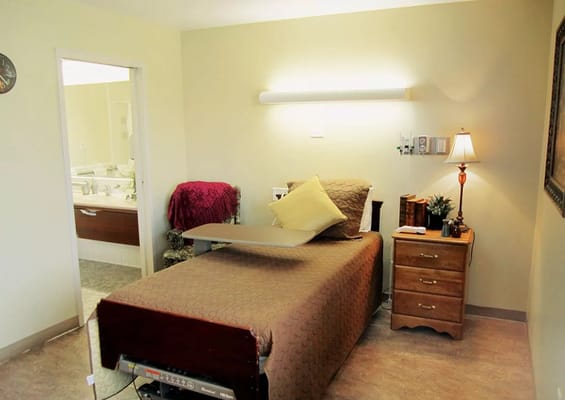 A cozy bedroom featuring a bed, nightstand, and accessible bathroom entrance.