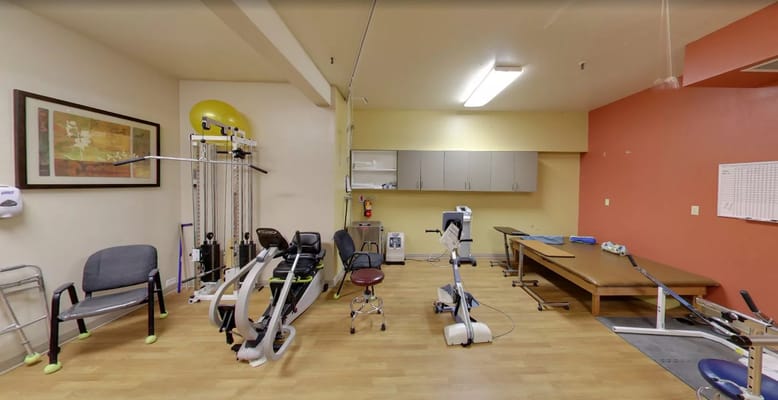 A spacious therapy room with exercise equipment and seating at Sandstone Richfield.