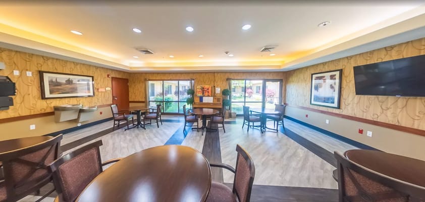 Spacious common area with tables and chairs, filled with natural light.