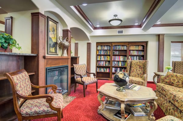 Comfortable seating area in the library with a fireplace and bookshelves