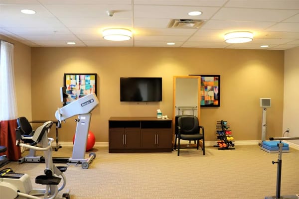 Well-equipped therapy room with exercise machines and seating