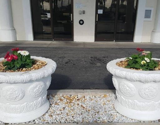 Two decorative flower planters with colorful flowers at the entrance of Seaside Manor