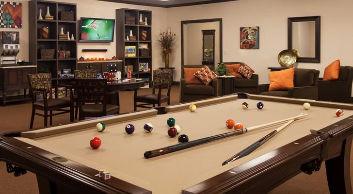 Billiards table with colorful balls and cues in a cozy recreation room.