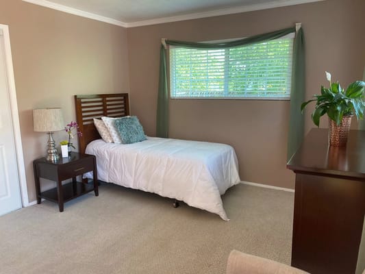 A cozy bedroom with a bed, nightstand, and window.