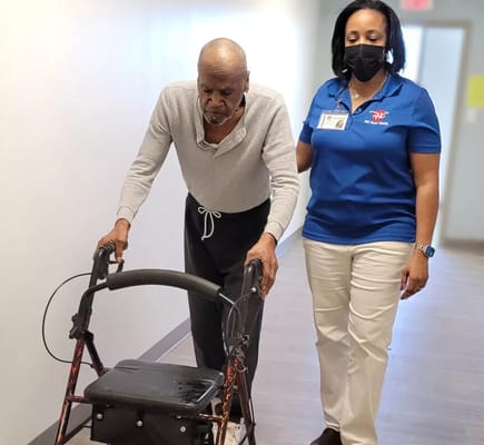 Staff assisting a resident with a walker in a hallway