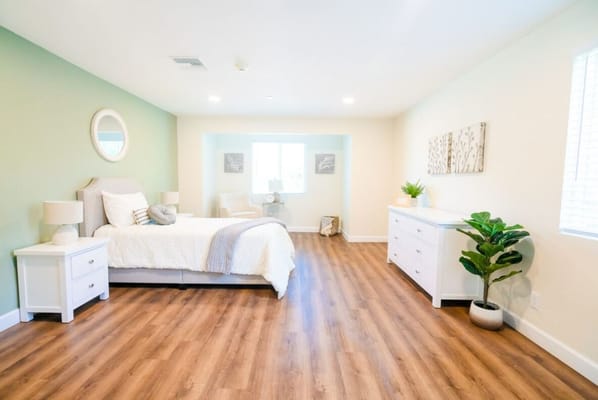 Spacious bedroom with a bed, nightstands, and a chair by the window
