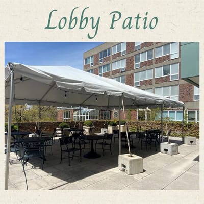 Outdoor lobby patio with tables and chairs under a tent
