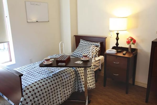 Comfortable bedroom with a bed, bedside table, lamp, and refreshments.