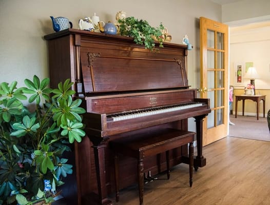 Wooden grand piano with plants in the Shore Pines Assisted Living facility.