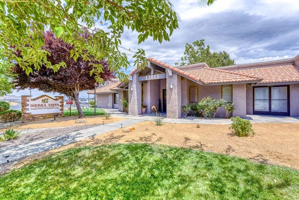 The entrance to Sierra Vista Independent & Assisted Living featuring a sign and landscaping.