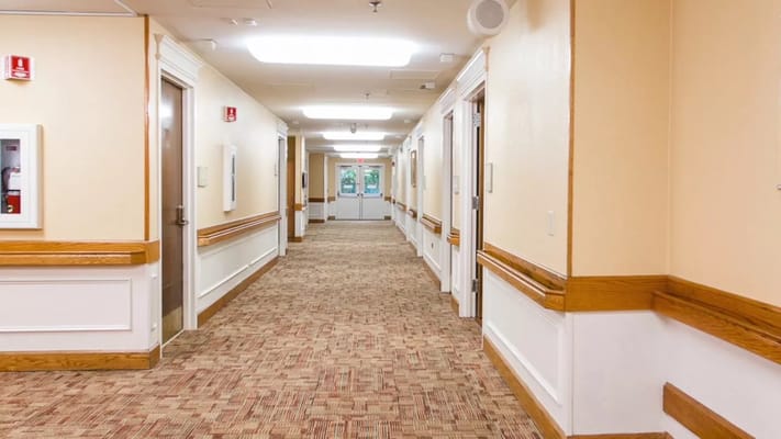 Brightly lit corridor with doors and carpet.