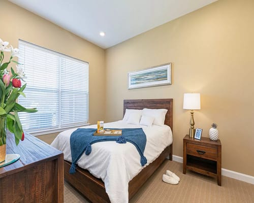 Cozy bedroom with a bed, bedside table, lamp, and window