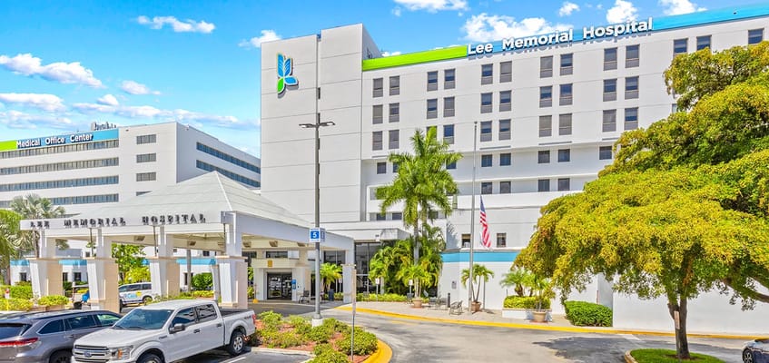 Exterior view of Lee Memorial Hospital with entrance and vehicles
