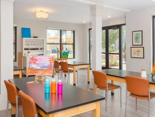 Art room with tables, painting supplies, and large windows