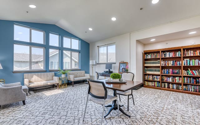 Bright common area with seating and a bookshelf at Solstice Senior Living