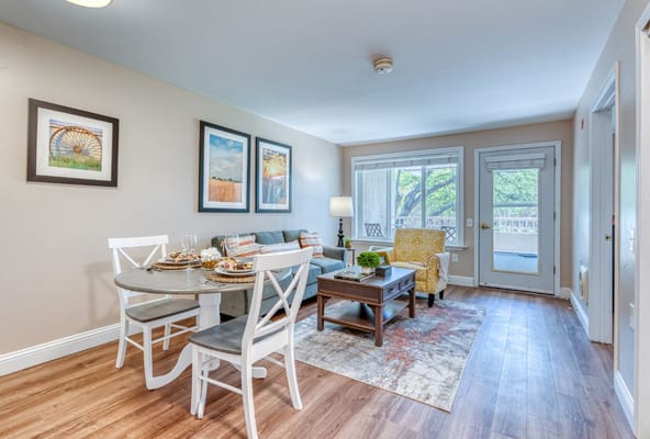 Living room featuring a dining table, comfortable seating, and large windows.