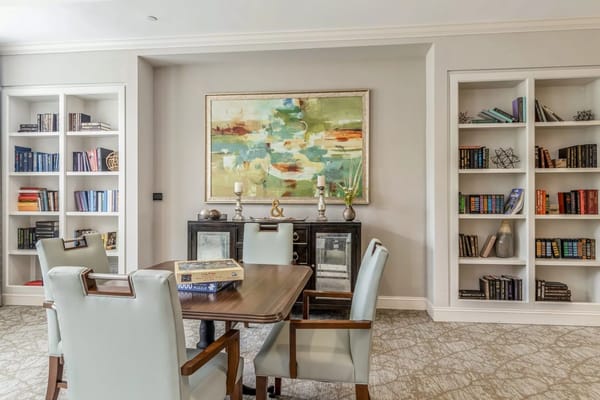 Cozy dining area with a wooden table and shelves filled with books.