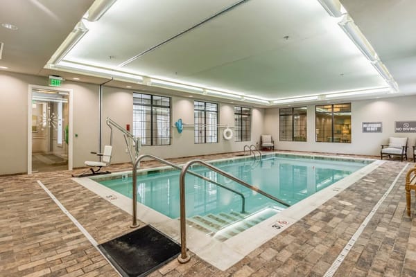 Indoor swimming pool with seating and windows