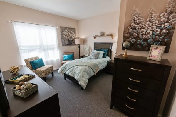 A cozy bedroom with a bed, dresser, and decorative items.