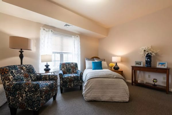 Cozy bedroom featuring floral armchairs, a single bed, and a desk.