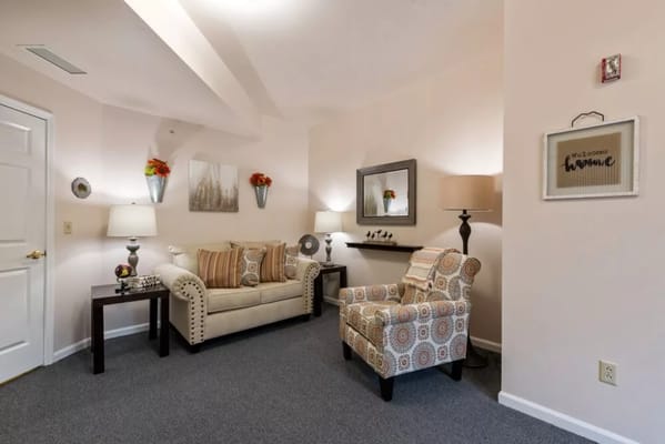 A cozy living room featuring a couch, armchair, and decorative elements.