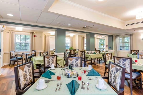 Dining room with green tablecloths and chairs in Sonata Coconut Creek.