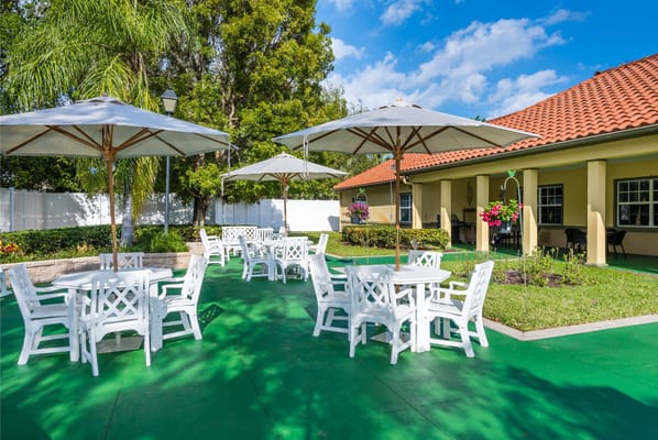 Bright outdoor dining area with white furniture and umbrellas.