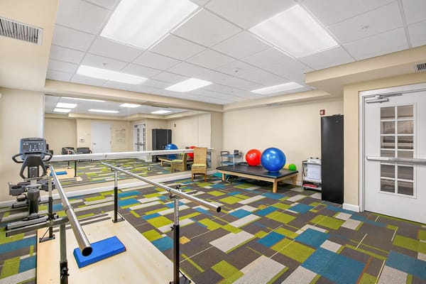 Interior view of the therapy room with exercise equipment and colorful flooring.
