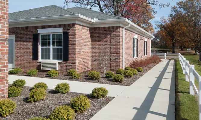 Exterior of South Breeze Senior Living showing brick building and landscaped pathway.
