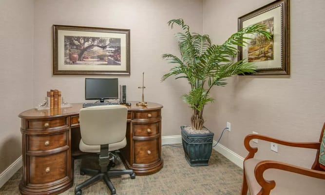 A small office space with a desk, computer, and potted plant.