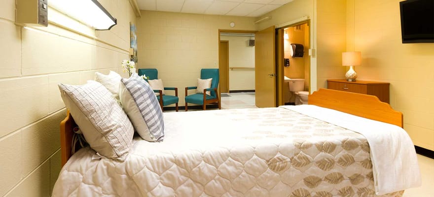 Cozy bedroom with a bed, seating area, and bathroom door.