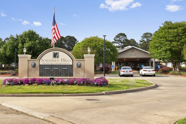 Entrance sign of Southern Hills Healthcare and Rehabilitation with flower beds and trees