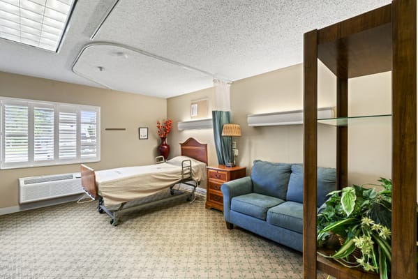 Cozy patient bedroom with bed, armchair, and decorative items