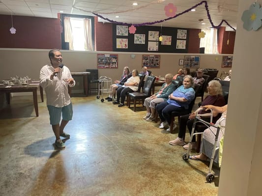A man speaking to a group of seated seniors during an activity session.