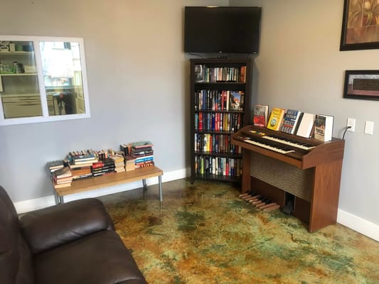 A reading area with bookshelves, a small table with books, and an organ.