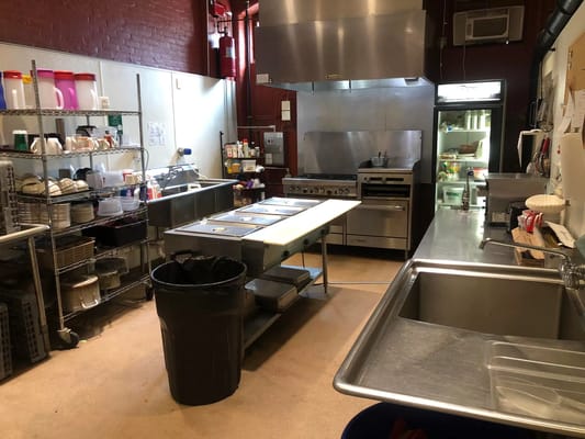 Commercial kitchen showing stainless steel equipment and storage racks