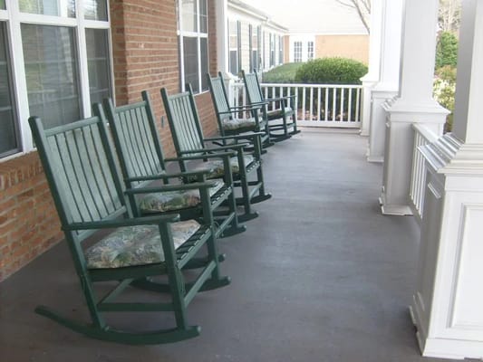 Row of green rocking chairs on a porch