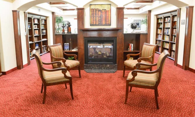 Seating area with two striped chairs near a fireplace and bookshelves