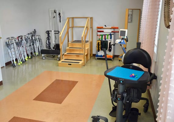 A rehabilitation room featuring stairs, exercise equipment, and mobility aids.
