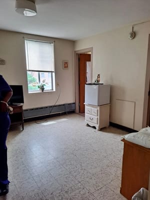 Interior of a senior living room with a small fridge and TV.