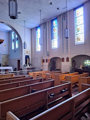 Interior view of the chapel with stained glass windows and wooden pews.