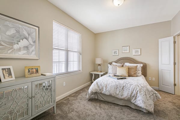 A well-decorated bedroom featuring a bed, lamp, and decorative furnishings.