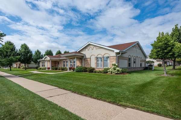Bright exterior of St. Catherine Commons with landscaped lawn and cloudy skies.