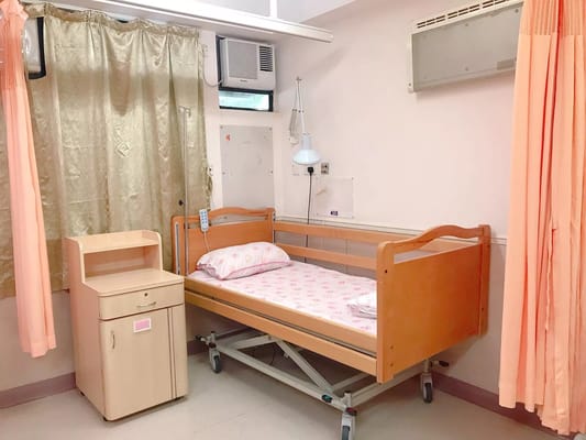 Cozy bedroom with a wooden bed, bedside table, and curtains.
