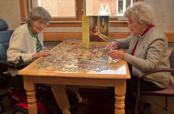 Two senior women working on a jigsaw puzzle at a table