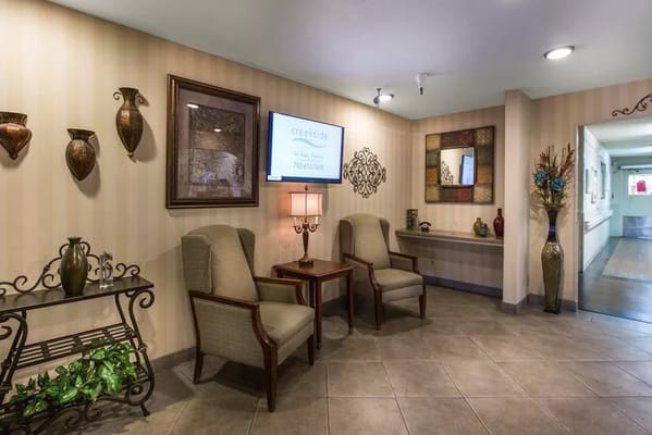 Lobby seating area with decorative wall art and a television.